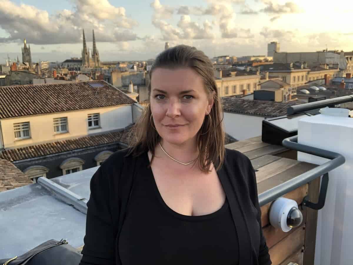 A woman on a rooftop with the city of Bordeaux, France in the background