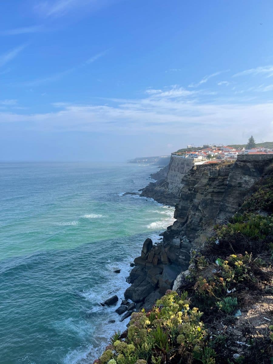 Dramatic view of rocky cliffs plunging into the turquoise waters along the coastline near Azenhas do Mar village.