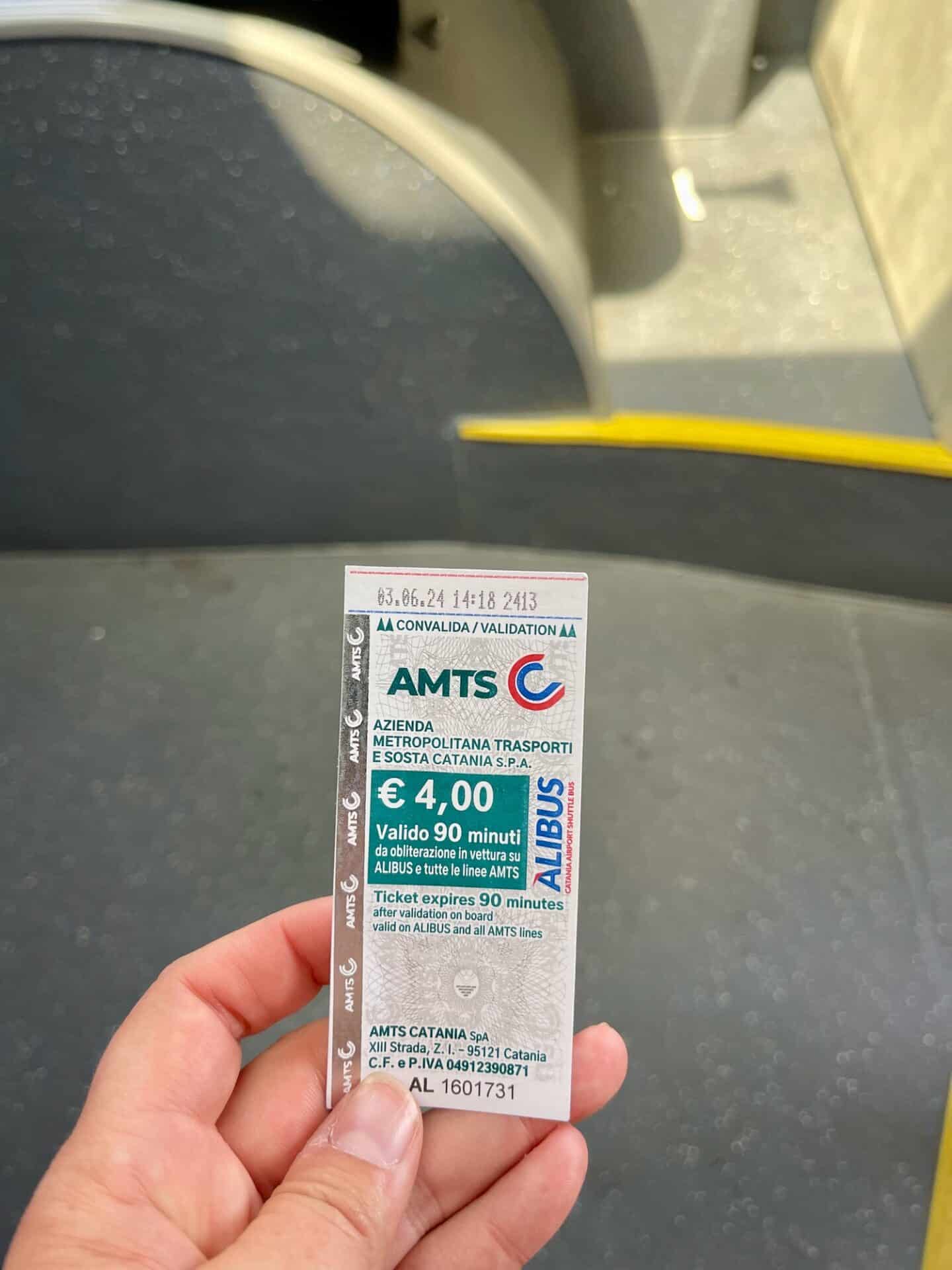 Hand holding a bus ticket for AMTS Catania.
