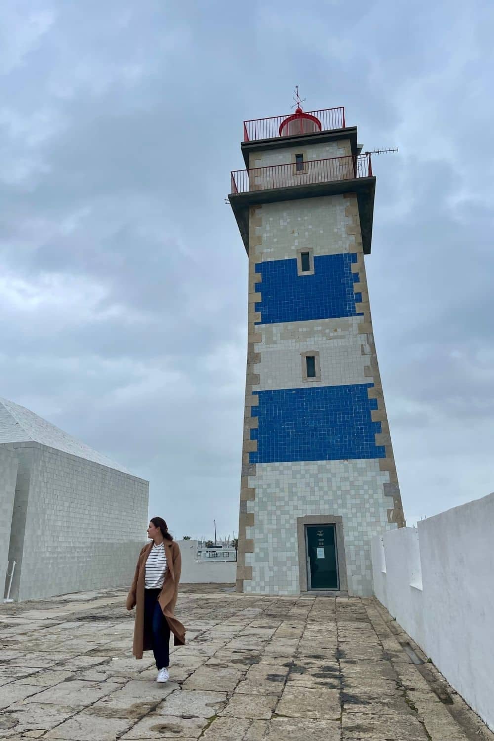 A woman alone with a lighthouse in the background. 