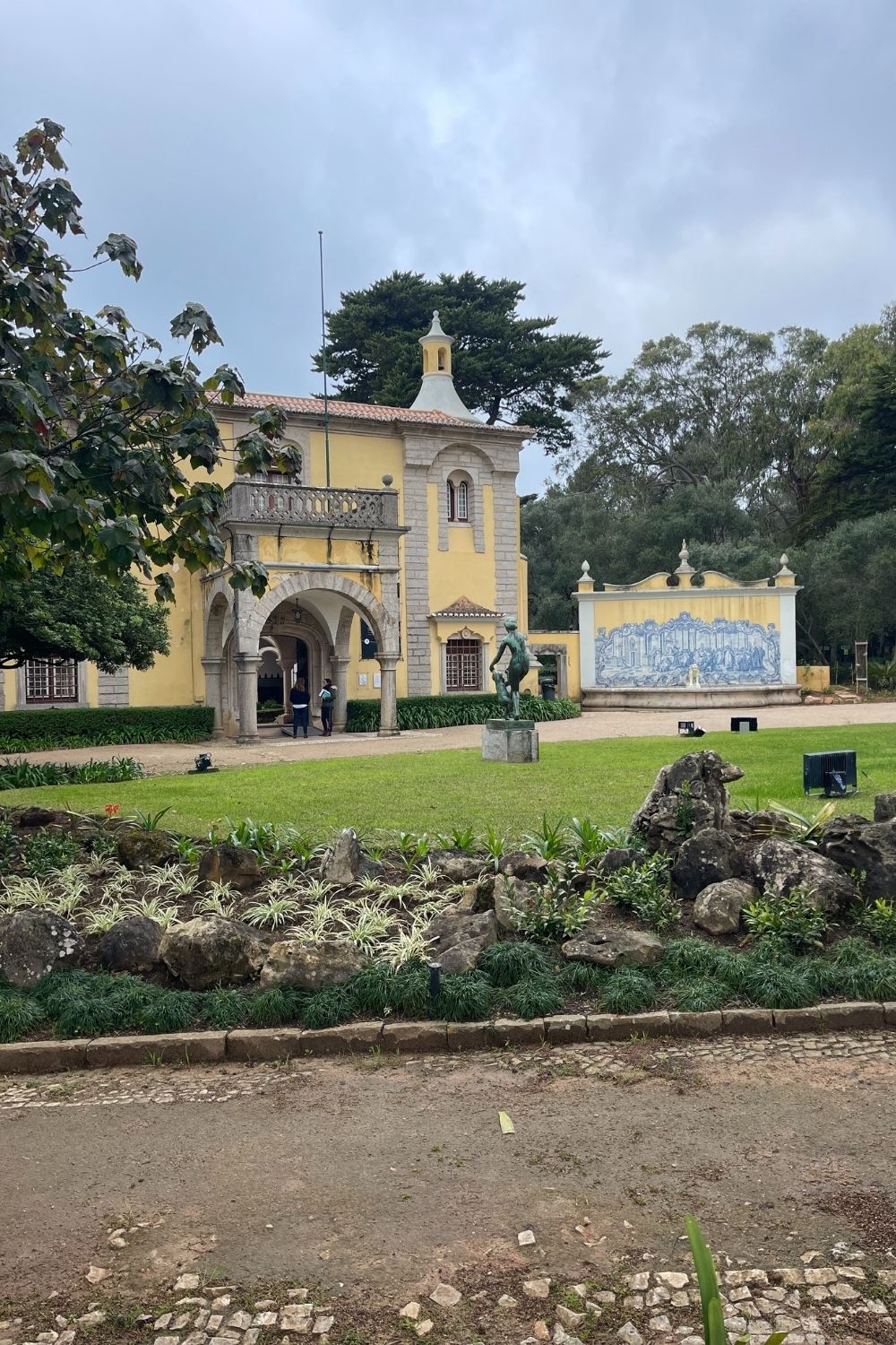 A historic yellow building with a garden and a blue tile panel.