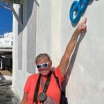 A woman wearing sunglasses pointing at a sign that says Coco