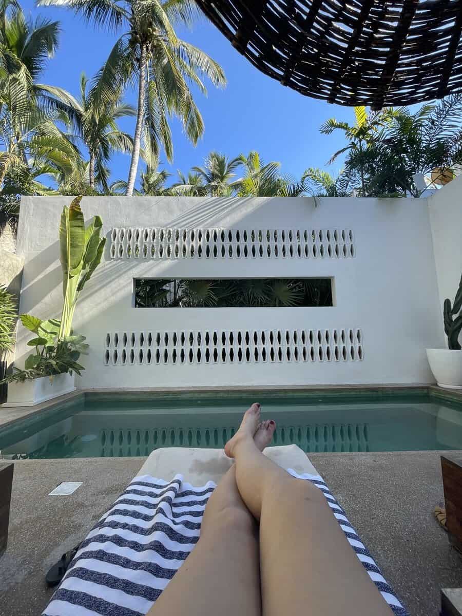 a womans legs on a lounge chair with the pool