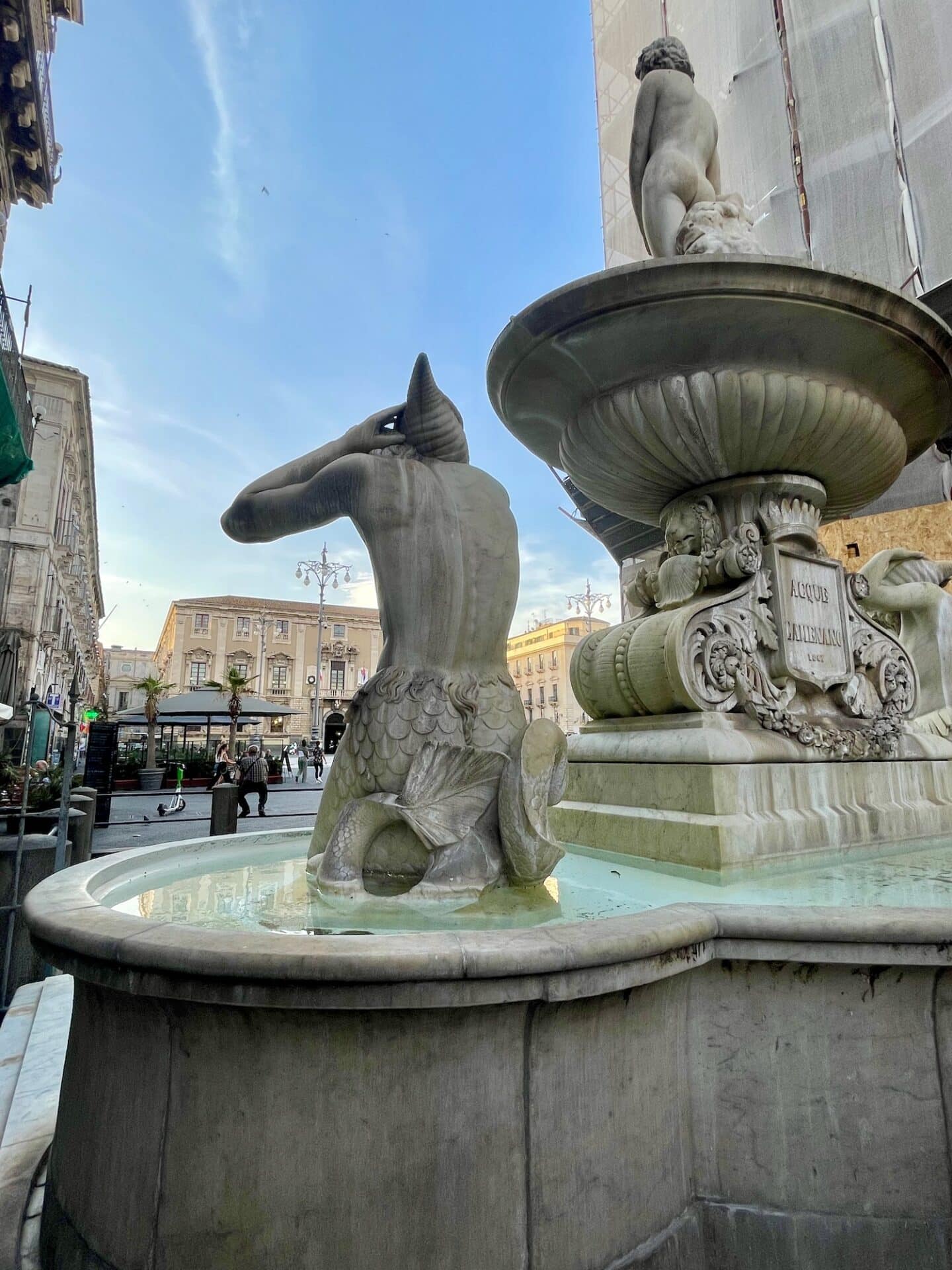 Close-up view of the iconic Fontana dell'Elefante in Catania, Italy, showcasing the detailed sculpture and fountain against a backdrop of historic architecture and a clear blue sky.