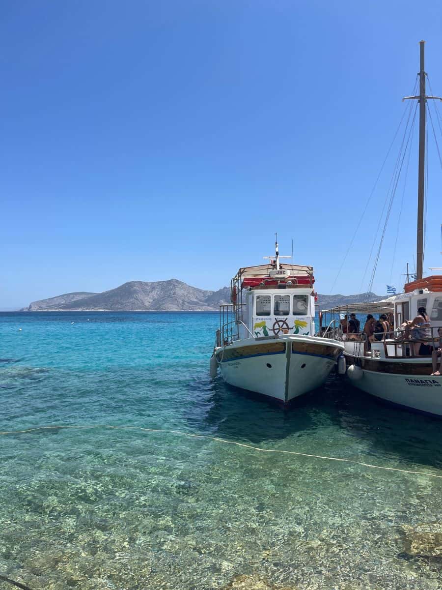 Tour boats moored in clear turquoise waters near a Greek island in Summer