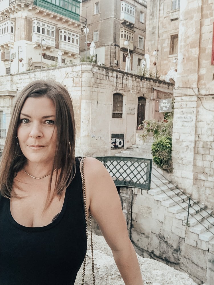A woman standing alone taking a selfie in Valletta