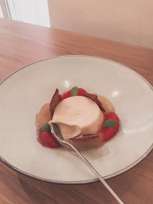 Dessert of a custard in a bowl with berries. 