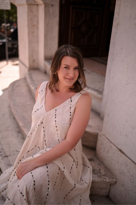 A woman sitting on the steps of a marble building.