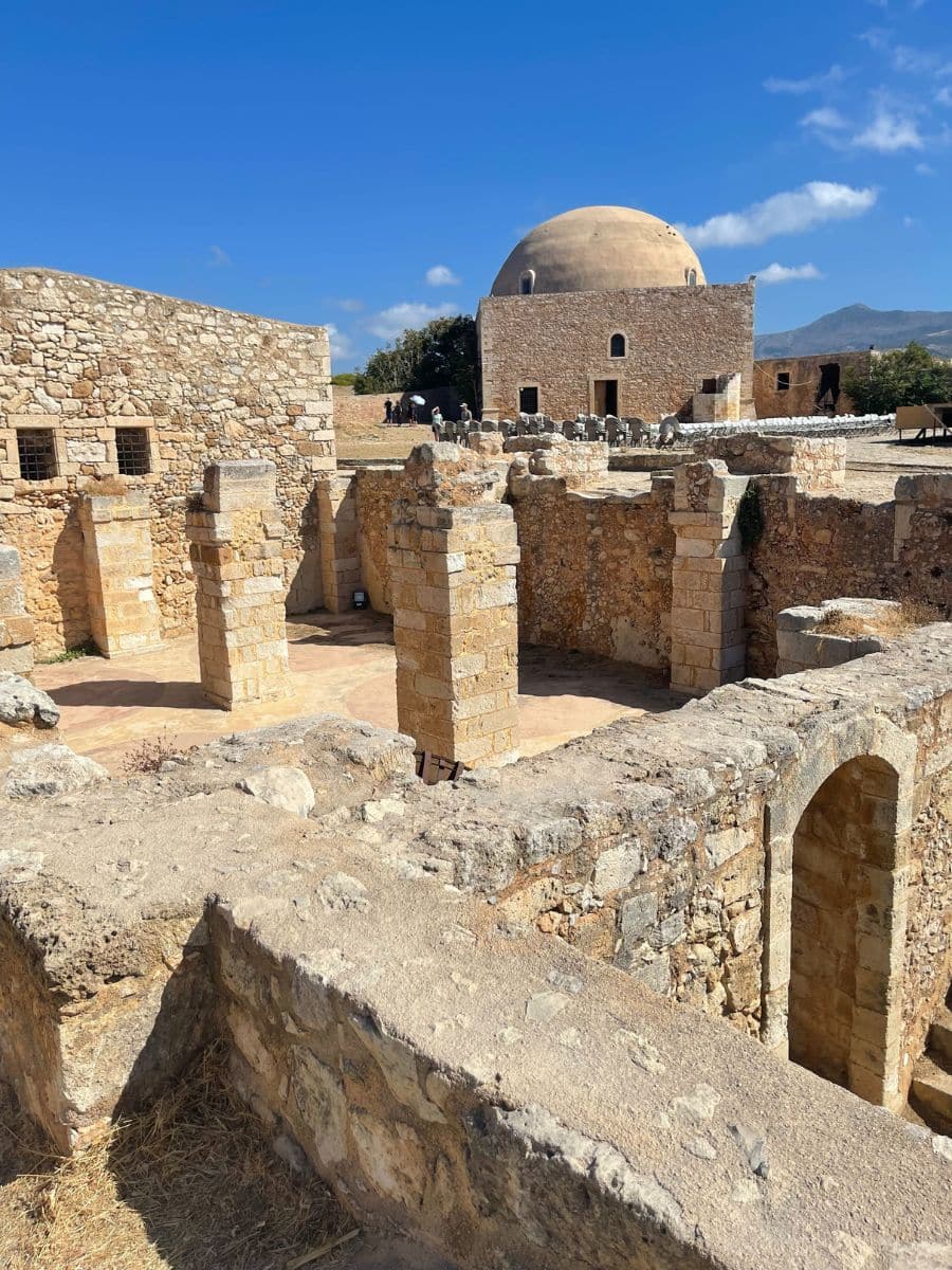 Historic ruins of an ancient building with stone columns under a clear blue sky in Crete, showcasing the island's rich archaeological heritage.