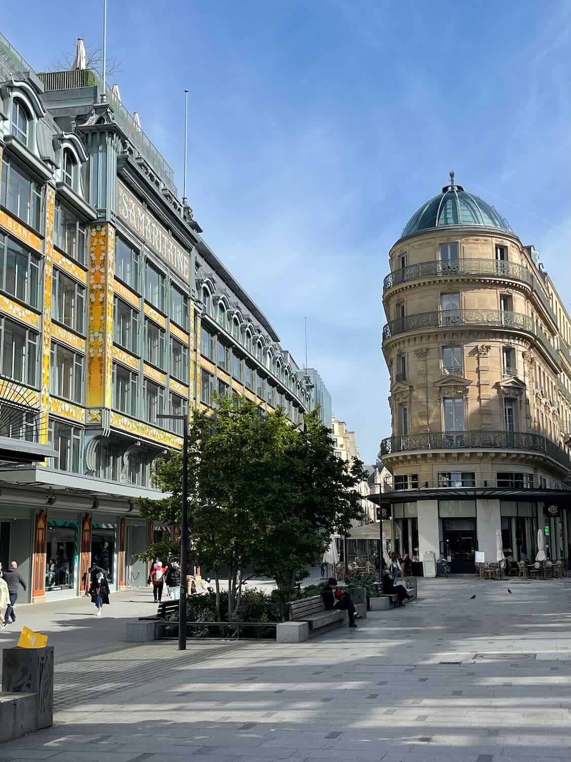 A bustling shopping street in Paris, with modern architecture and pedestrians enjoying a sunny day, reflecting the lively urban life and fashion culture of the city.