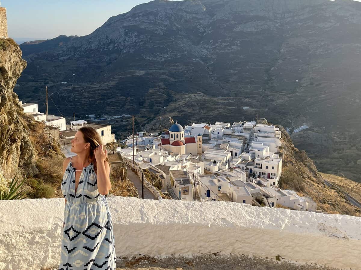 A woman in Serifos Greece at sunset with the classic greek town in the distance. 