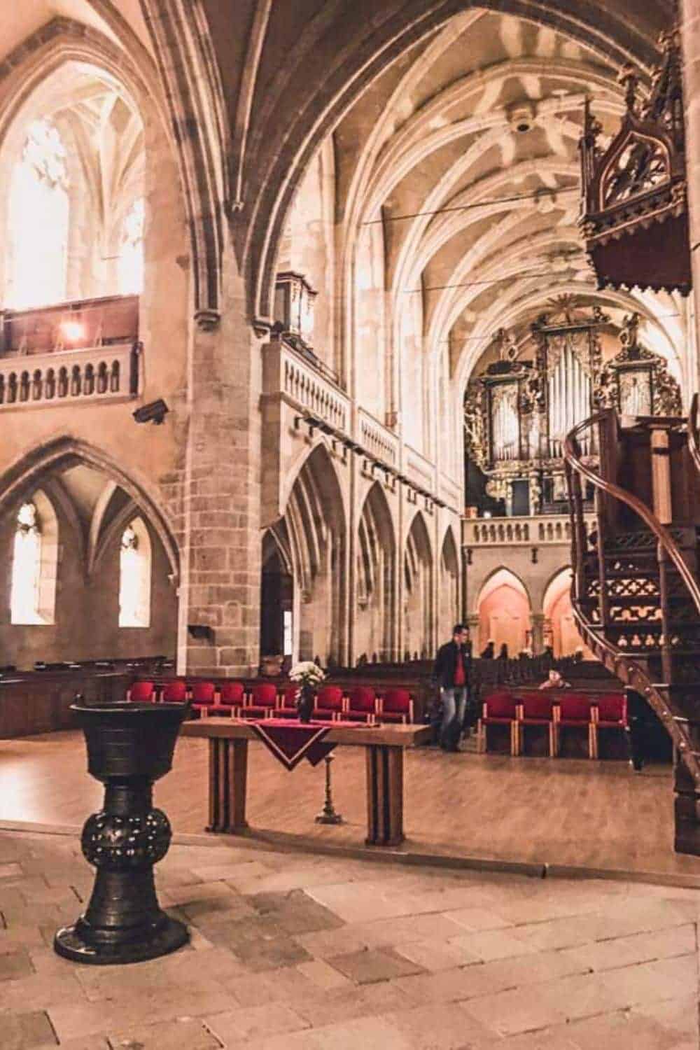 Interior of the Lutheran Cathedral in Sibiu, with rows of red pews and a grand pipe organ, illustrating the city's rich cultural heritage 