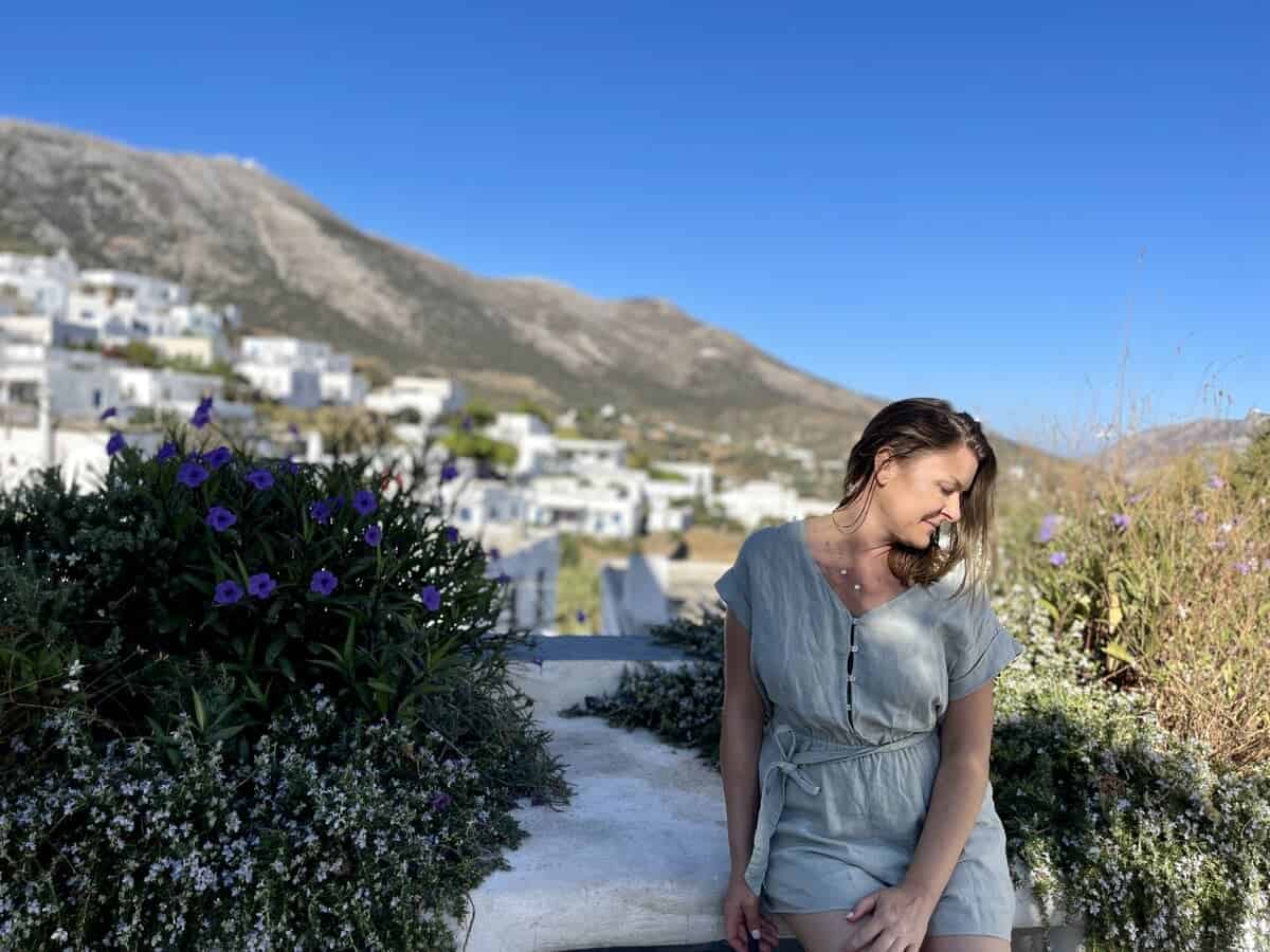 A solo woman sitting on the bench in Sifnos, Greece with the white homes in the background