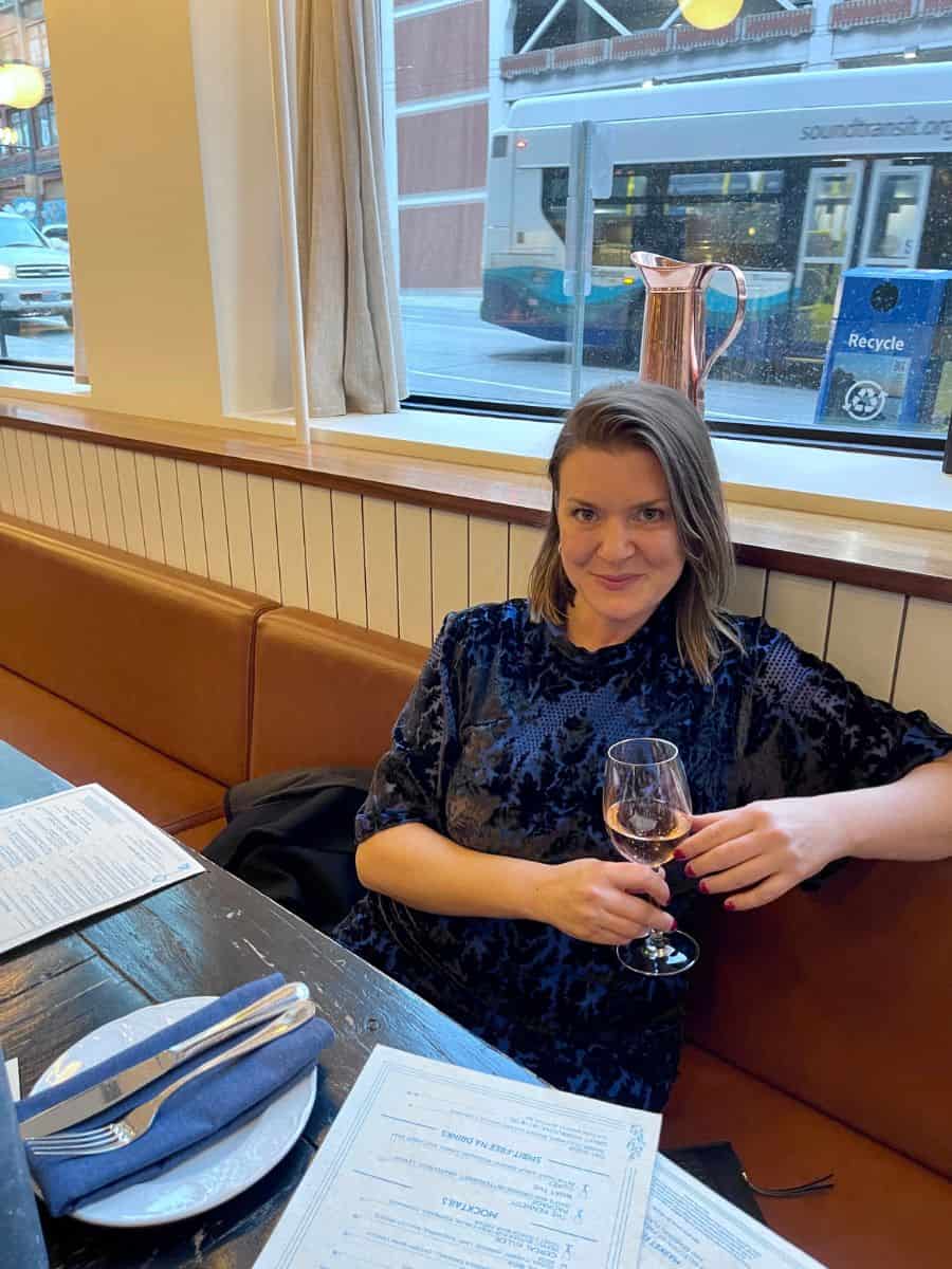 A Woman in a restaurant alone holding a drink