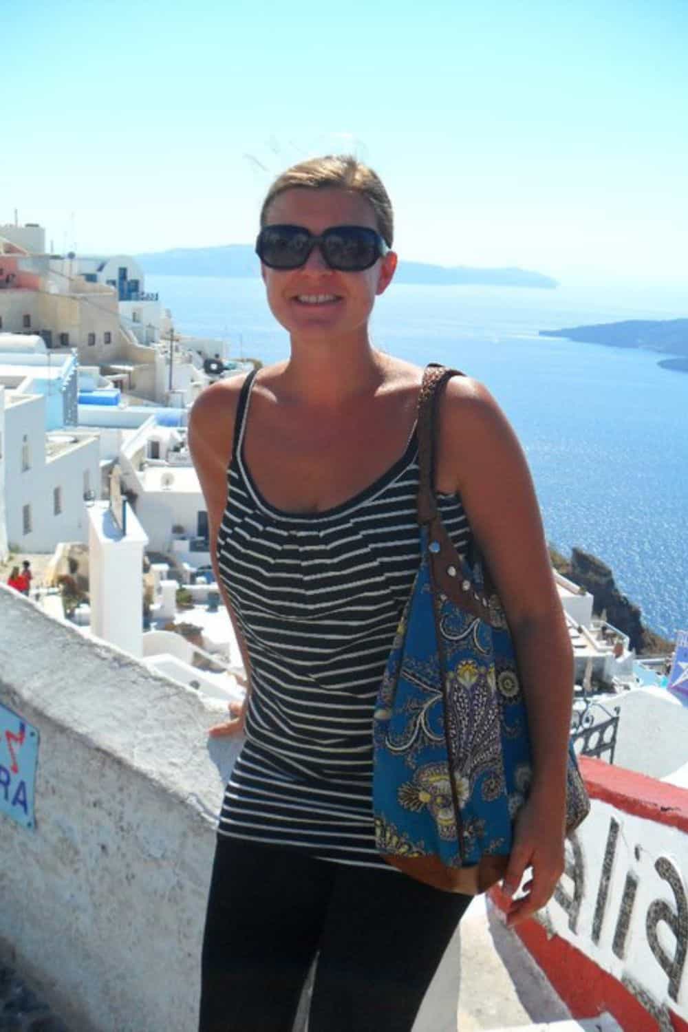 A woman traveling in her 20s with the ocean in the distance. 