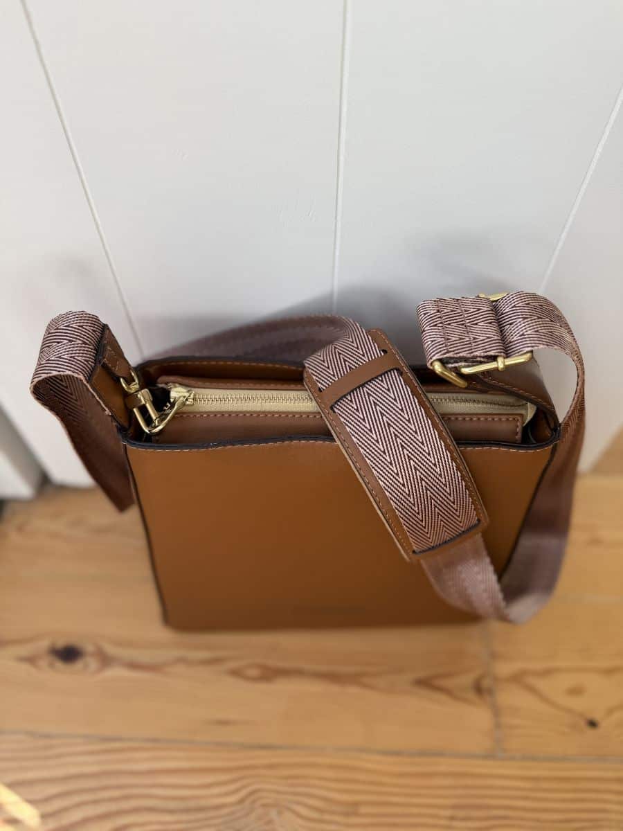 Close-up view of the Thafeal purse showing the secure top zipper and wide strap detail.