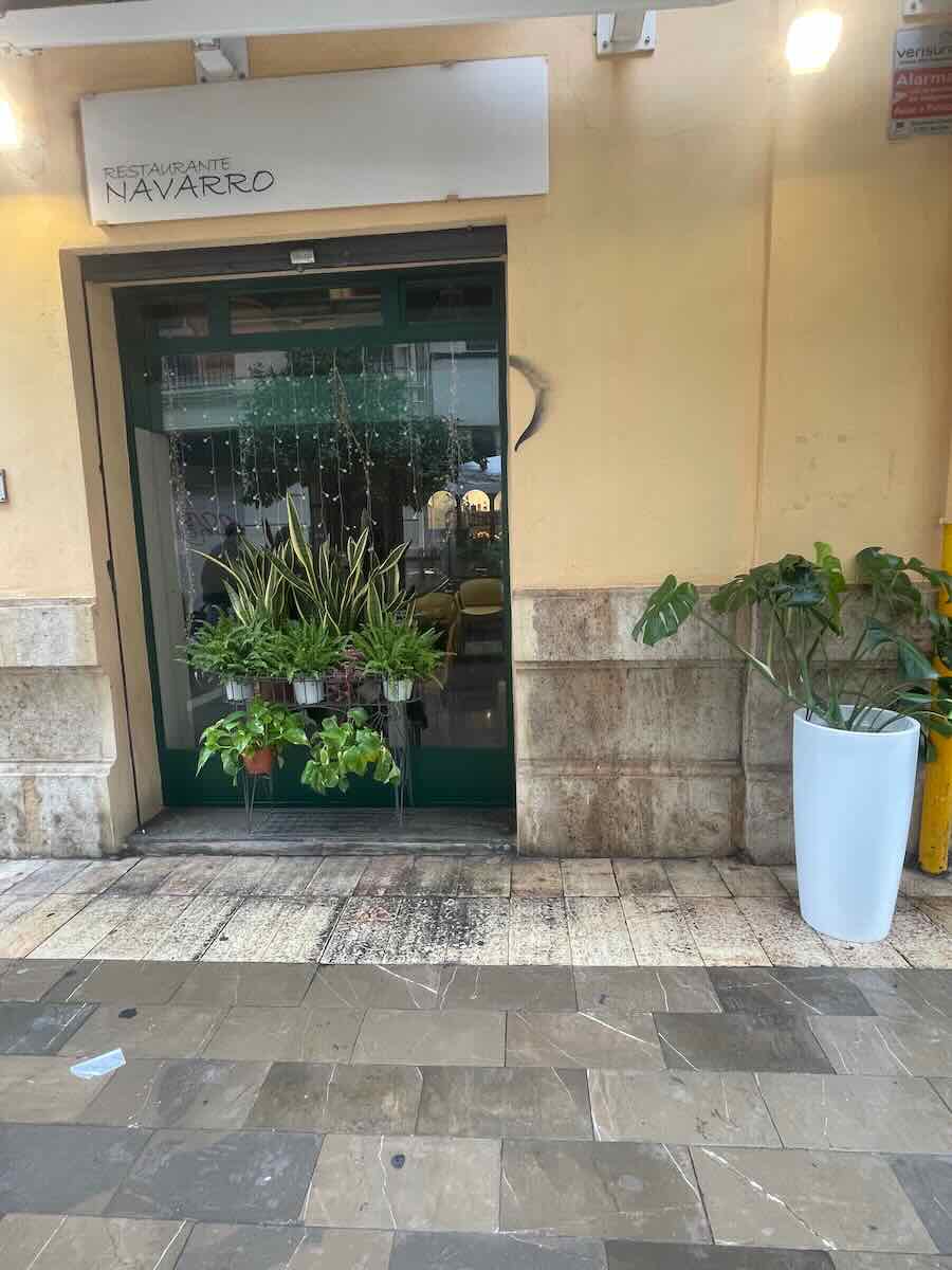 Exterior of Restaurante Navarro in Valencia, with green plants by the entrance, offering a welcoming spot to experience local dining.