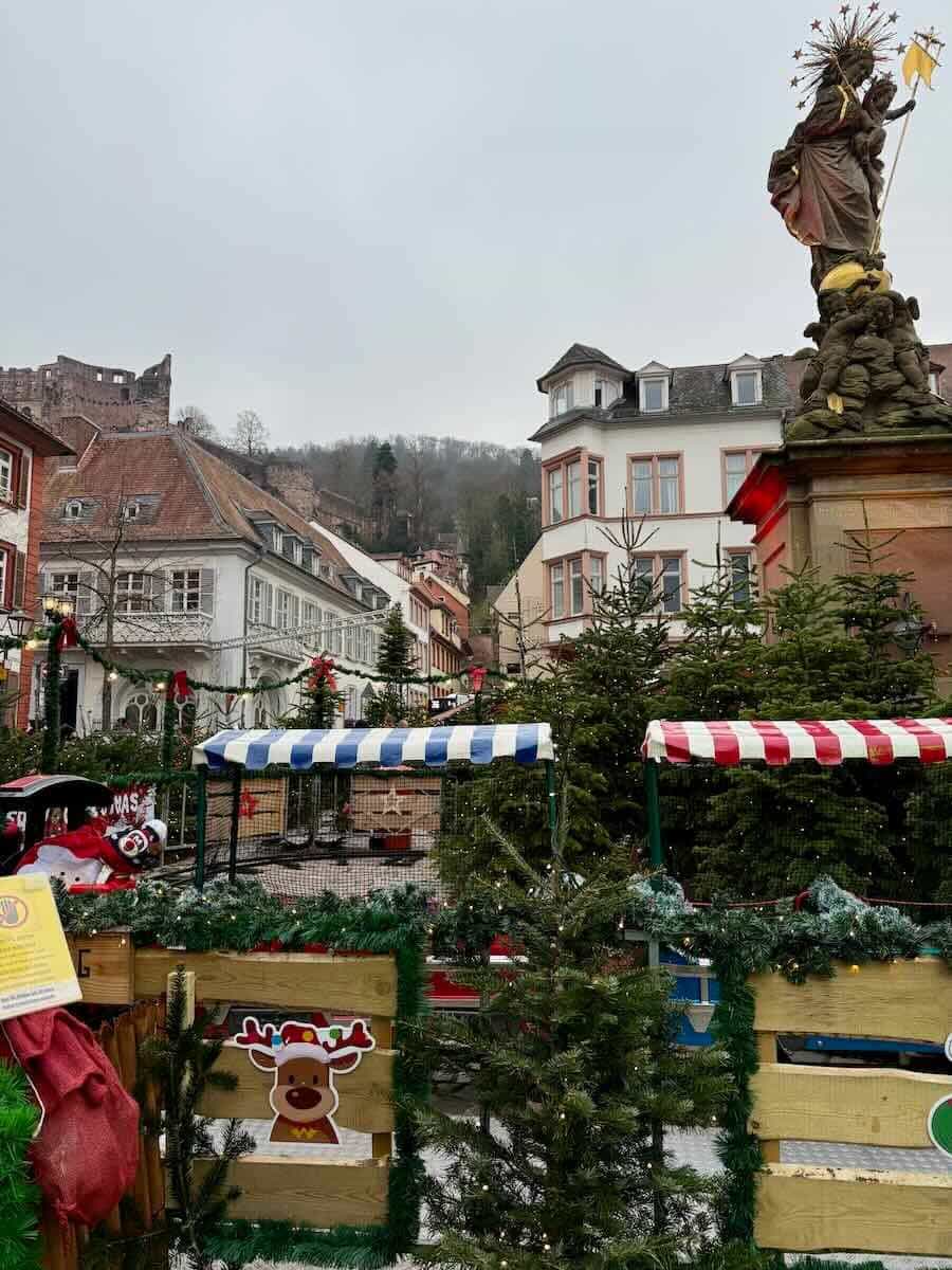 Christmas market setup in Heidelberg, Germany, with festive decorations and the Heidelberg Castle in the background