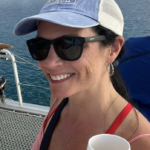 A woman in sunglasses holding a white cup